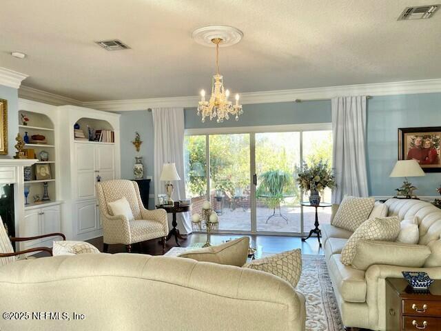 living room with a chandelier, wood-type flooring, a fireplace, and ornamental molding