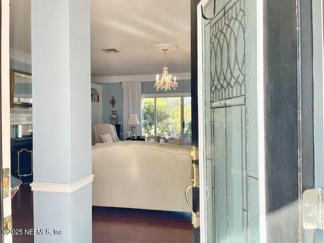 interior space featuring dark wood-type flooring, a notable chandelier, and ornamental molding