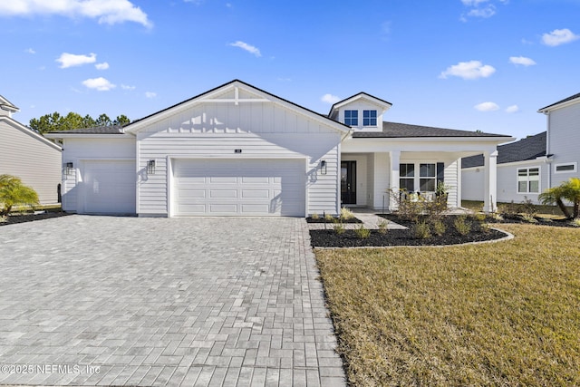 view of front of home featuring a garage, a front yard, and a porch