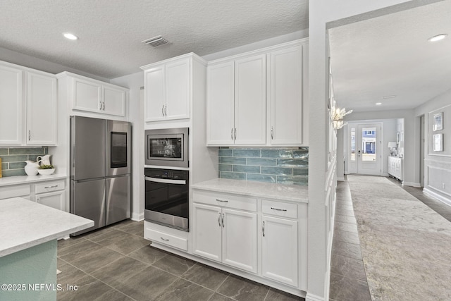 kitchen featuring white cabinetry, appliances with stainless steel finishes, tasteful backsplash, and a textured ceiling