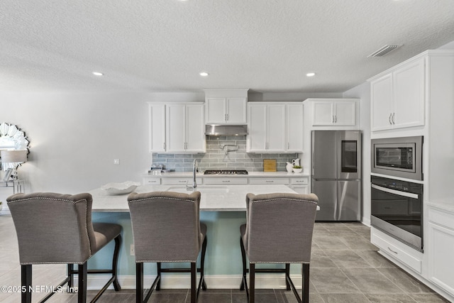 kitchen with white cabinetry, appliances with stainless steel finishes, a kitchen breakfast bar, and decorative backsplash