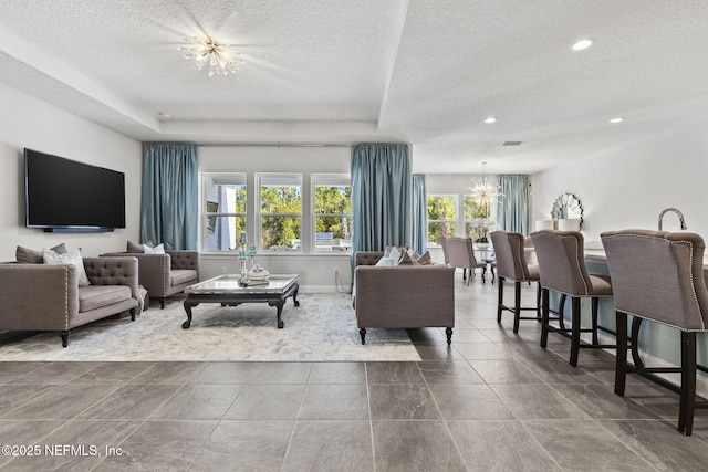 living room with a notable chandelier, a raised ceiling, and a textured ceiling