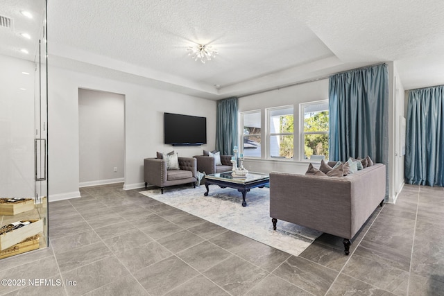 living room featuring a chandelier, a textured ceiling, and a tray ceiling