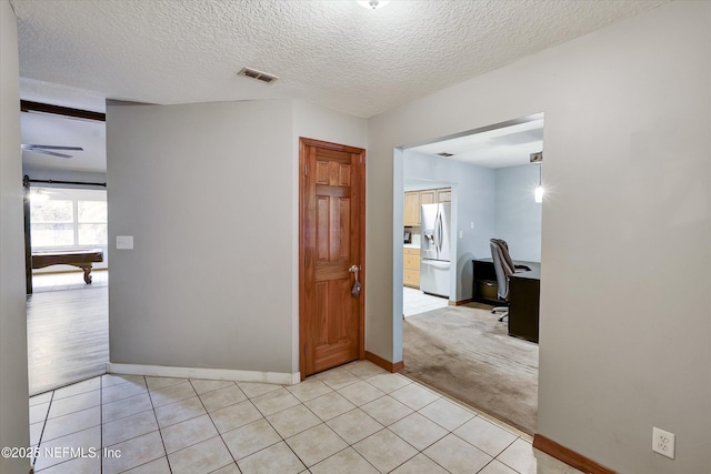 corridor featuring a textured ceiling and light tile patterned floors