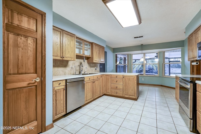 kitchen featuring kitchen peninsula, appliances with stainless steel finishes, decorative backsplash, hanging light fixtures, and sink