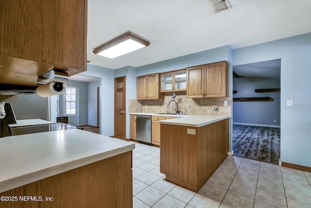 kitchen featuring light tile patterned floors, kitchen peninsula, dishwasher, and sink