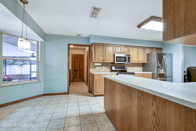 kitchen featuring light tile patterned floors, appliances with stainless steel finishes, tasteful backsplash, and decorative light fixtures