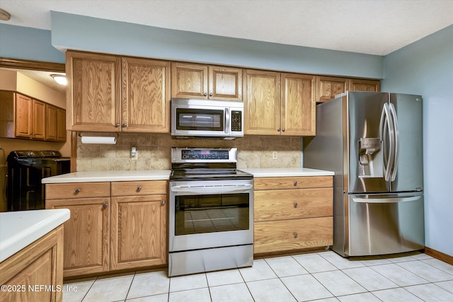 kitchen featuring light tile patterned floors, backsplash, separate washer and dryer, and stainless steel appliances