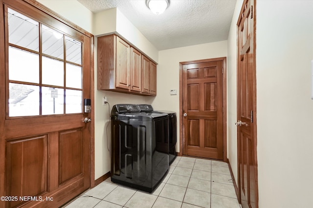 clothes washing area with a textured ceiling, cabinets, light tile patterned flooring, and washing machine and clothes dryer