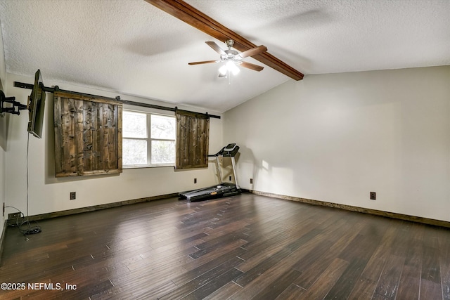 exercise area with a barn door, vaulted ceiling, dark wood-type flooring, and a textured ceiling