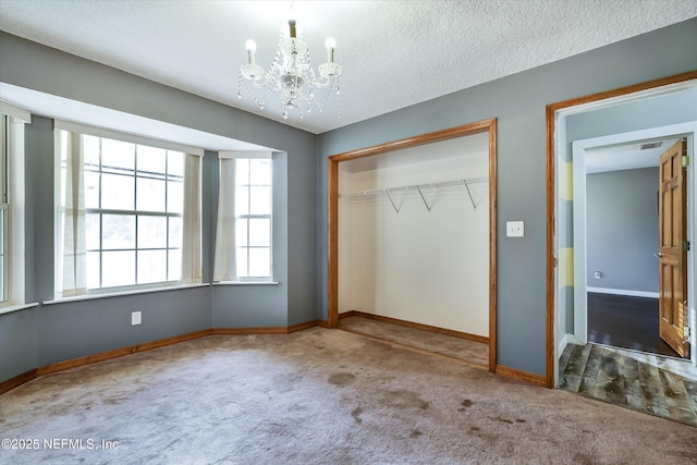 unfurnished bedroom featuring carpet floors, a textured ceiling, a closet, and a chandelier