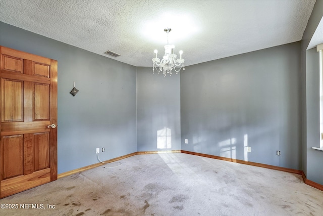 carpeted spare room featuring a notable chandelier and a textured ceiling