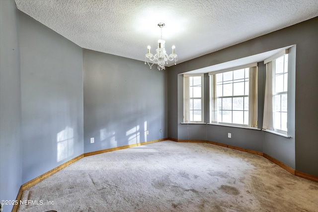 spare room with carpet floors, an inviting chandelier, and a textured ceiling