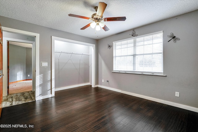 unfurnished bedroom featuring ceiling fan, a closet, dark hardwood / wood-style flooring, and a textured ceiling