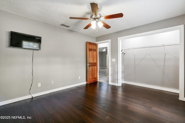 unfurnished bedroom featuring ceiling fan, a closet, dark hardwood / wood-style floors, and a textured ceiling