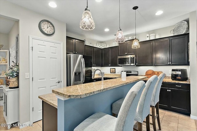 kitchen with pendant lighting, light tile patterned floors, a center island with sink, and stainless steel appliances