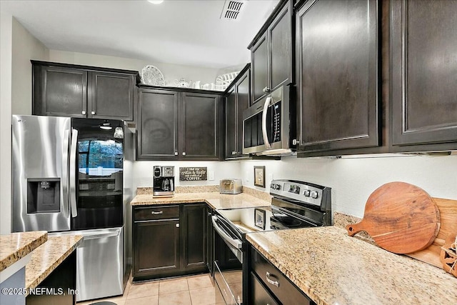 kitchen featuring light stone countertops, light tile patterned floors, appliances with stainless steel finishes, and dark brown cabinets