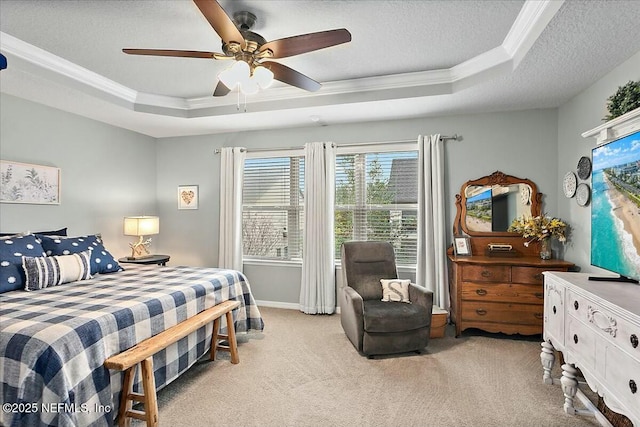 bedroom featuring a textured ceiling, ornamental molding, light colored carpet, ceiling fan, and a tray ceiling