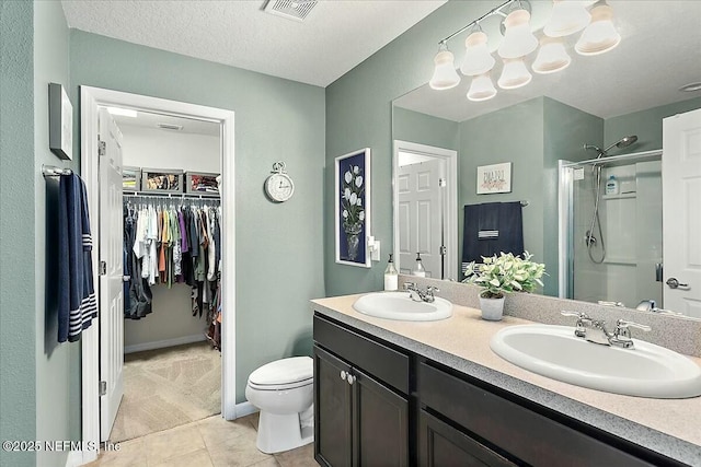 bathroom with a textured ceiling, walk in shower, vanity, and tile patterned flooring