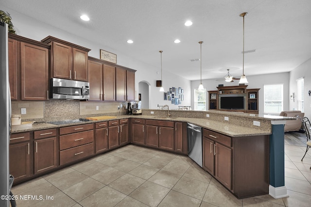 kitchen featuring appliances with stainless steel finishes, tasteful backsplash, decorative light fixtures, stone countertops, and sink