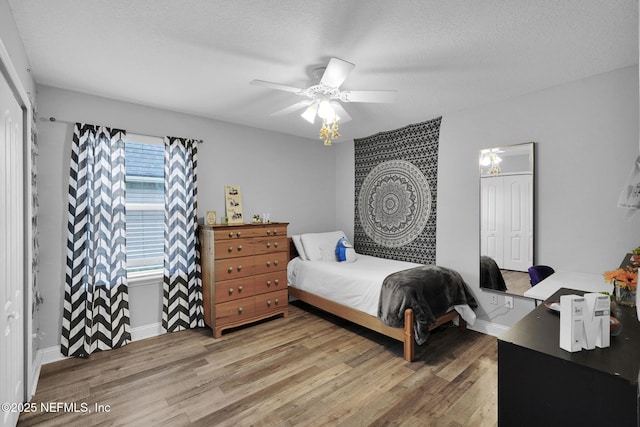 bedroom with a textured ceiling, a closet, hardwood / wood-style flooring, and ceiling fan