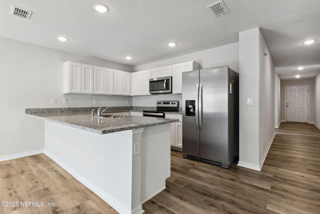 195 River Rdg Pl, Welaka, FL 32193 - kitchen featuring sink, white cabinetry, appliances with stainless steel finishes, kitchen peninsula, and dark stone counters