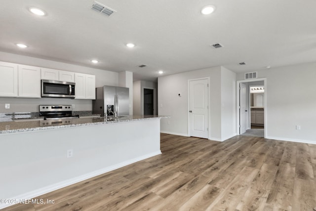 195 River Rdg Pl, Welaka, FL 32193 - kitchen with white cabinetry, wood-type flooring, light stone countertops, and appliances with stainless steel finishes