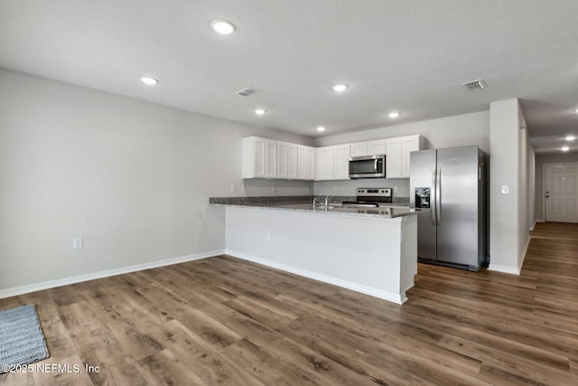 195 River Rdg Pl, Welaka, FL 32193 - kitchen featuring appliances with stainless steel finishes, dark stone countertops, white cabinets, kitchen peninsula, and dark wood-type flooring