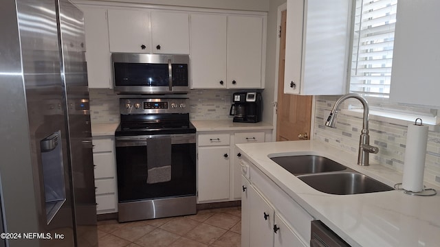 kitchen with stainless steel appliances, white cabinets, backsplash, and sink