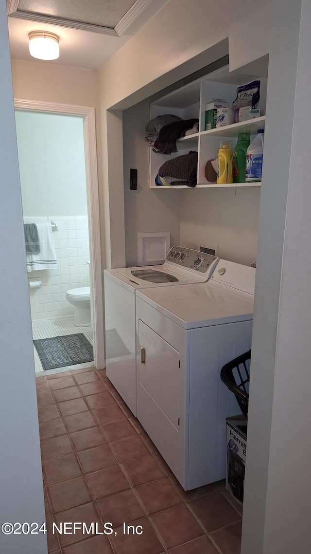 clothes washing area with washing machine and clothes dryer and dark tile patterned floors