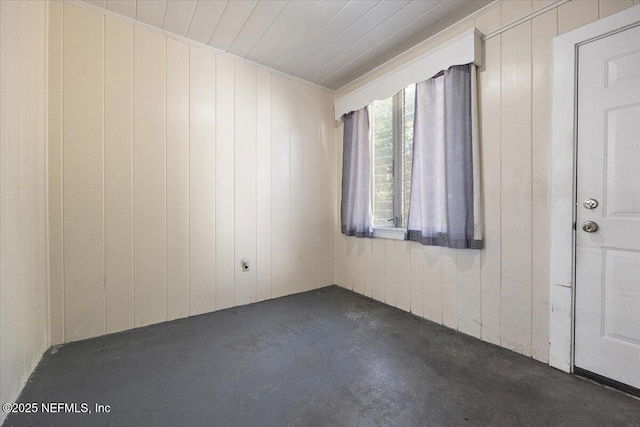 carpeted empty room with ornamental molding and wooden walls