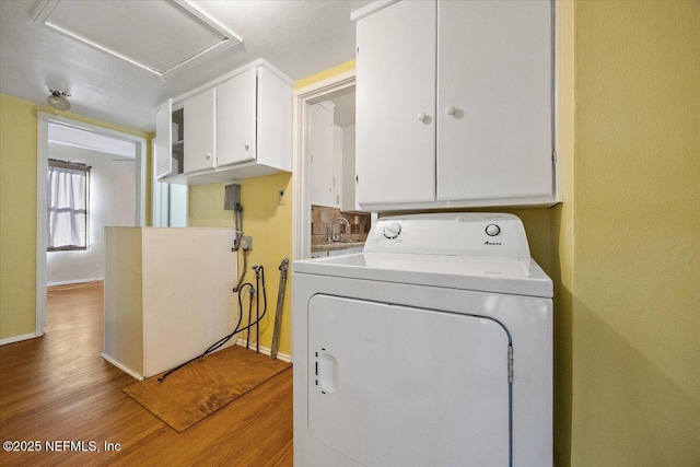 laundry room with light wood-type flooring, cabinets, and washer / clothes dryer