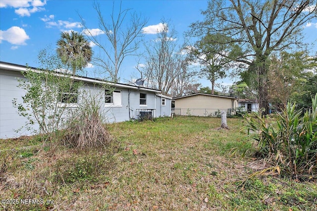 rear view of property featuring a yard and central AC