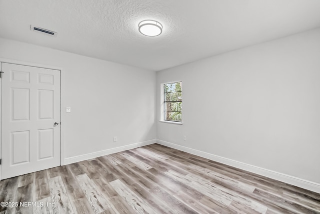 unfurnished room featuring a textured ceiling and light hardwood / wood-style flooring