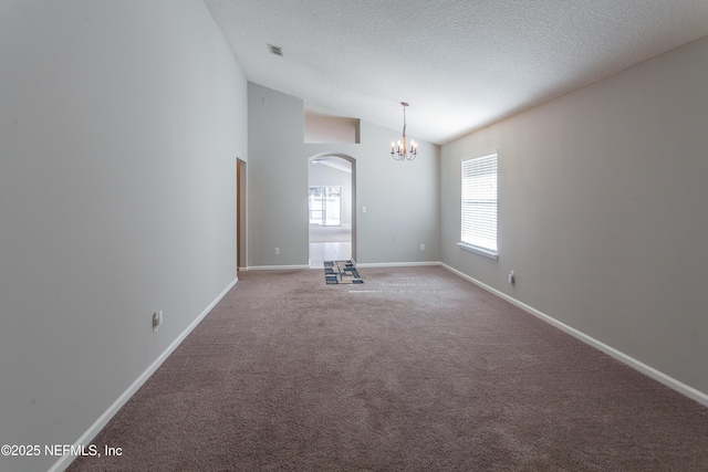 carpeted empty room featuring a textured ceiling, a chandelier, and lofted ceiling