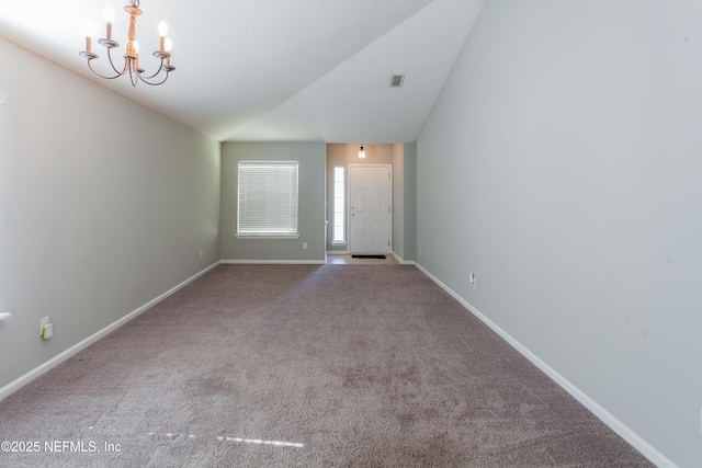 carpeted empty room featuring vaulted ceiling and a chandelier