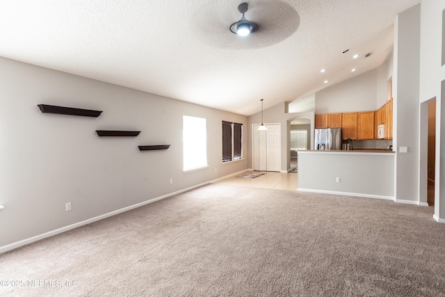 unfurnished living room featuring ceiling fan, light carpet, vaulted ceiling, and sink