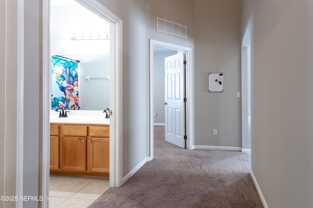 hallway with light colored carpet and sink