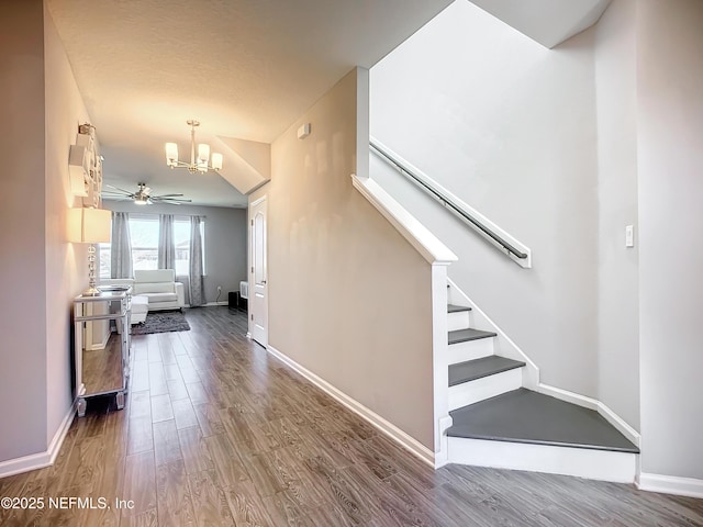 stairs featuring ceiling fan with notable chandelier and hardwood / wood-style floors