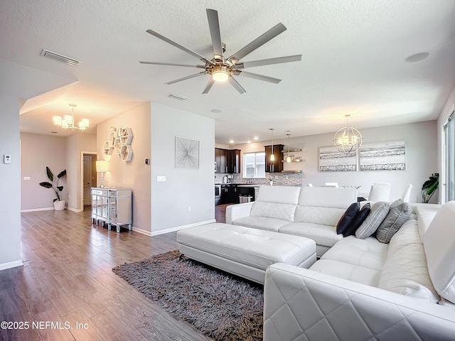 living room with a textured ceiling, ceiling fan with notable chandelier, and wood-type flooring