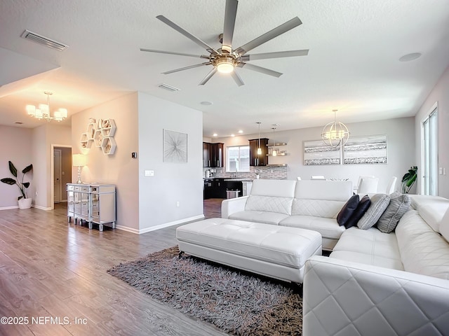 living room with a healthy amount of sunlight, dark hardwood / wood-style floors, and ceiling fan with notable chandelier