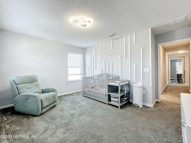 bedroom featuring carpet, a nursery area, and a textured ceiling