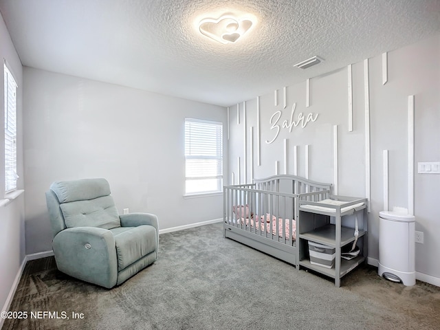 carpeted bedroom with a textured ceiling and a crib