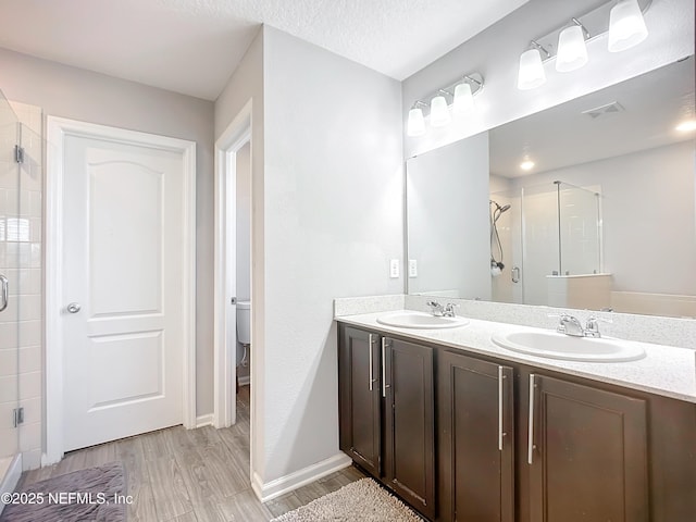 bathroom featuring toilet, vanity, walk in shower, hardwood / wood-style flooring, and a textured ceiling