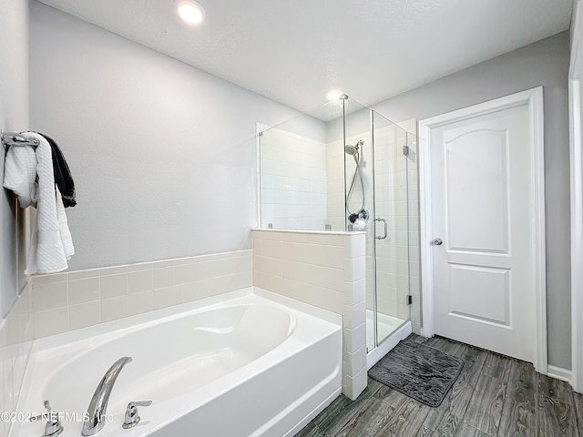 bathroom with a textured ceiling, independent shower and bath, and hardwood / wood-style flooring