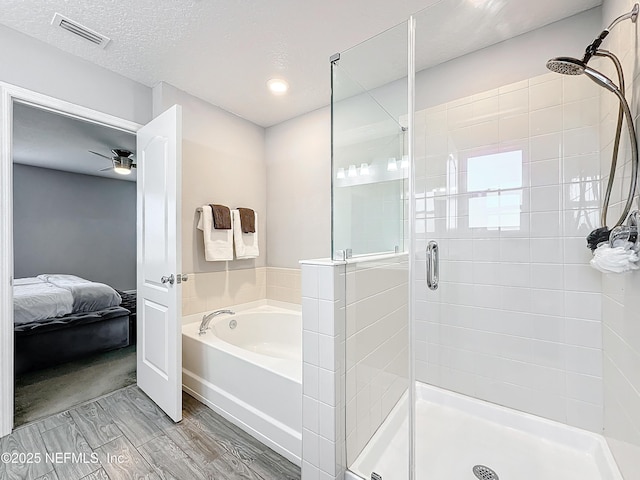 bathroom with separate shower and tub, ceiling fan, and a textured ceiling