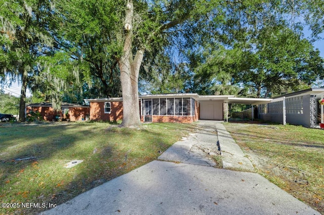 single story home with a front lawn, a sunroom, and a carport