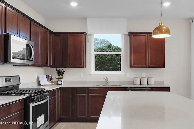 kitchen featuring light tile patterned floors, stainless steel appliances, decorative light fixtures, and sink