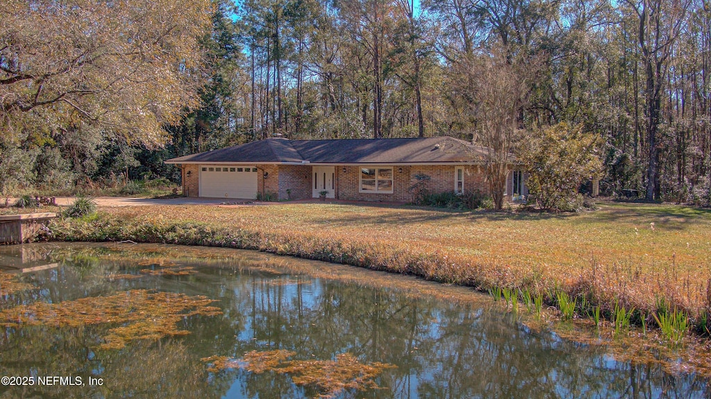 view of front facade with a front yard, a garage, and a water view