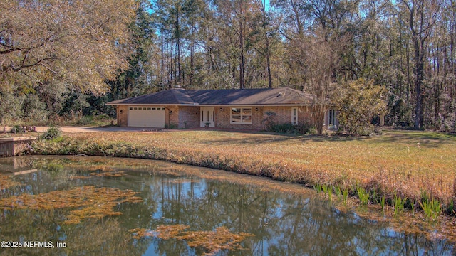 view of front facade with a front yard, a garage, and a water view